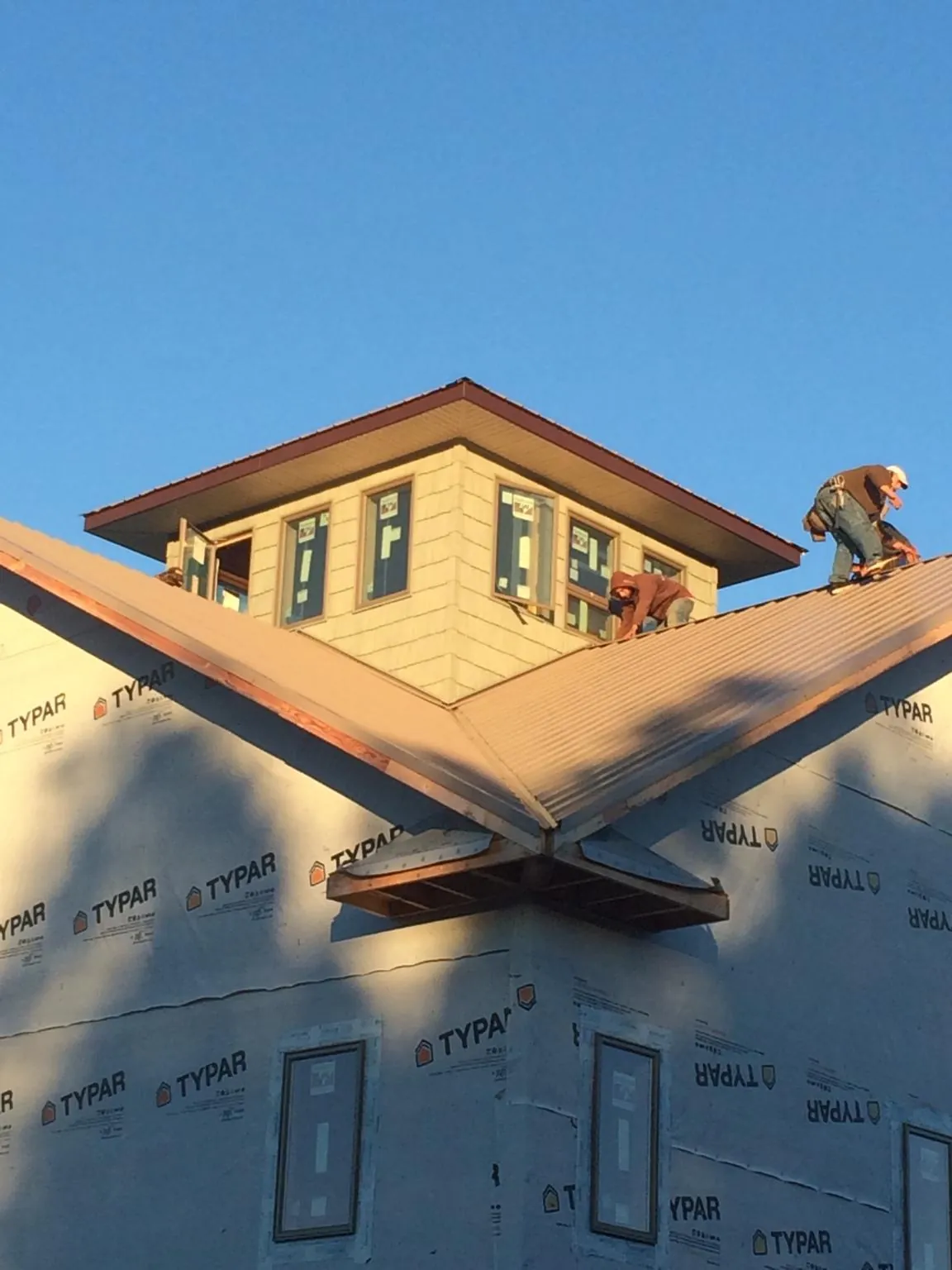 Roofers working around a rooftop cupola on a new metal roof at sunset — Roof Waterproofing in Independence by Roofing Brothers